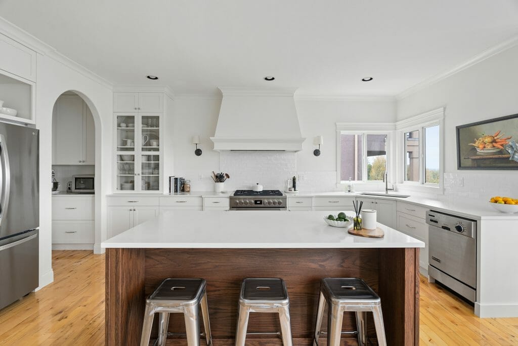 Panoramic view of a custom kitchen renovation in white with a large island finished in wood grain.