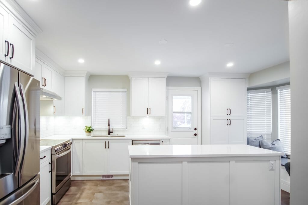 A new kitchen renovation shows the appliances, the kitchen island, and a bay window with seating.