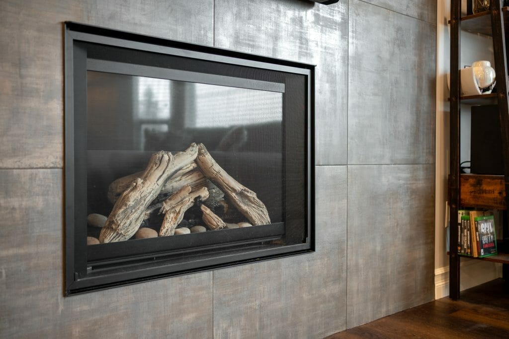 A modern gas fireplace set in a wall of large stone tiles.