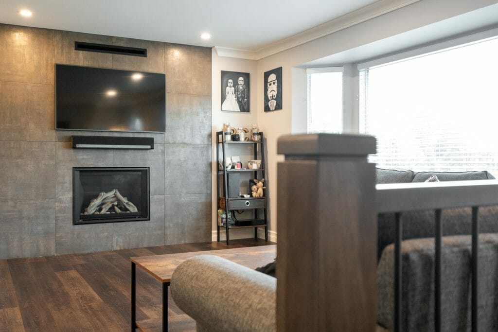A custom renovation with modern furniture and a fireplace with a flat-screen TV above.