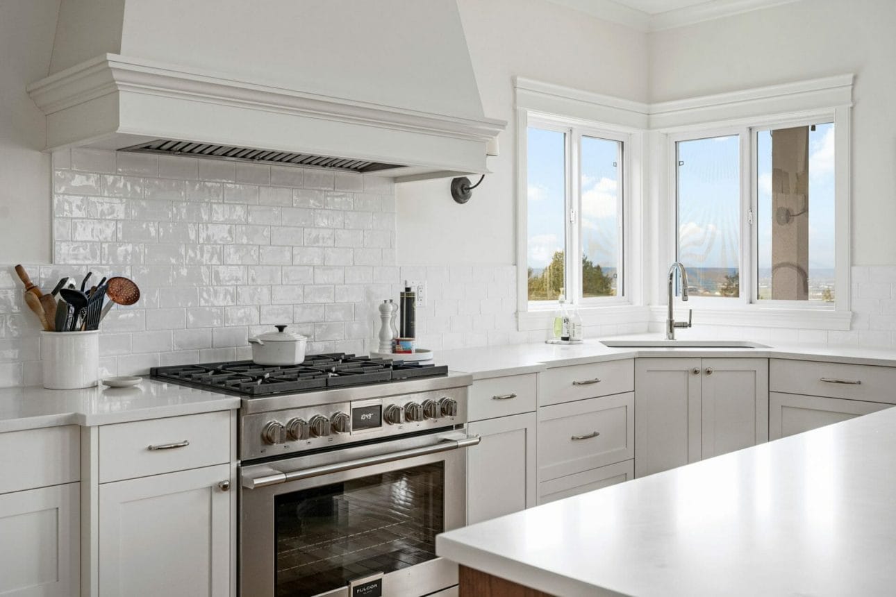 A modern kitchen renovation with a corner sink and a gas stove with a large enclosed stove fan.