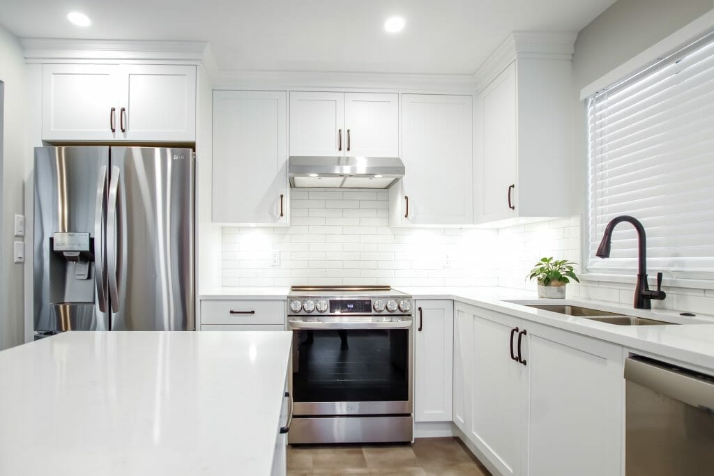 Stainless steel appliances in a newly renovated kitchen that is all in white.