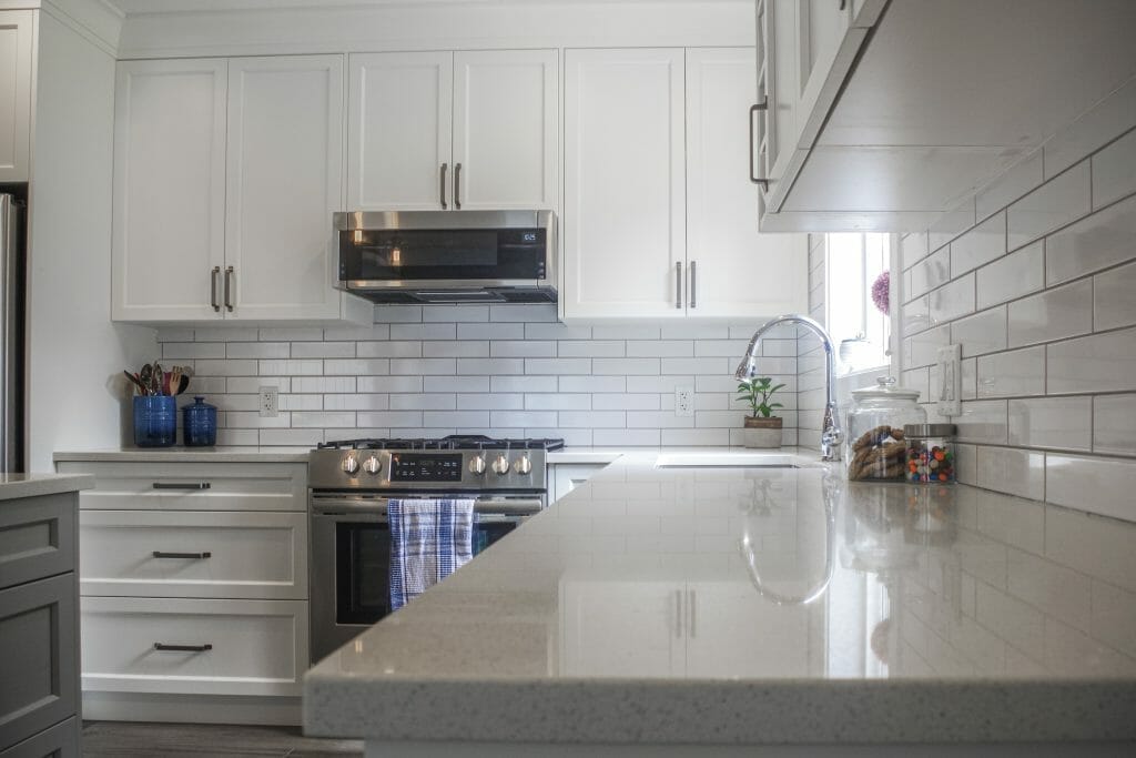 A modern kitchen renovation with Onyx countertops and white tile backsplash.