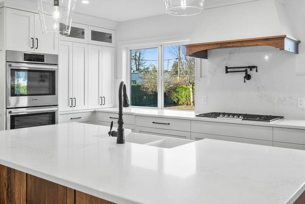 Newly renovated white kitchen with stainless steel appliances, gas stove and large kitchen island.