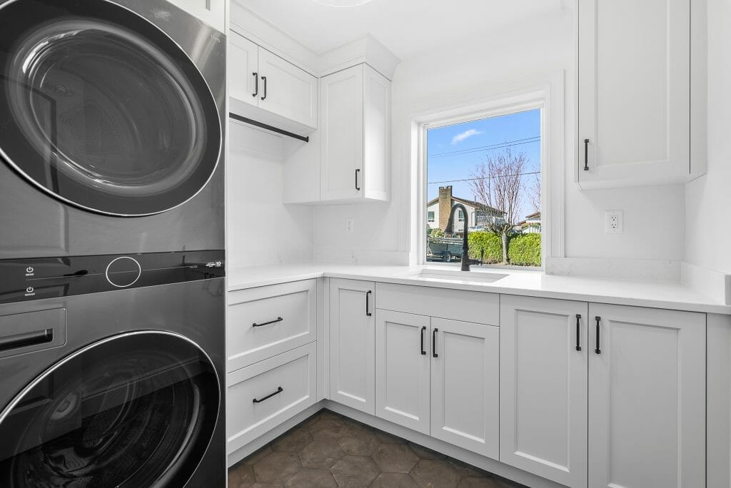 Newly renovated laundry room with white cabinets and stainless steel washer and dryer.