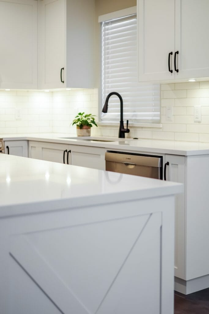A kitchen renovation showing the sink, quartz countertops and a window above the sink.