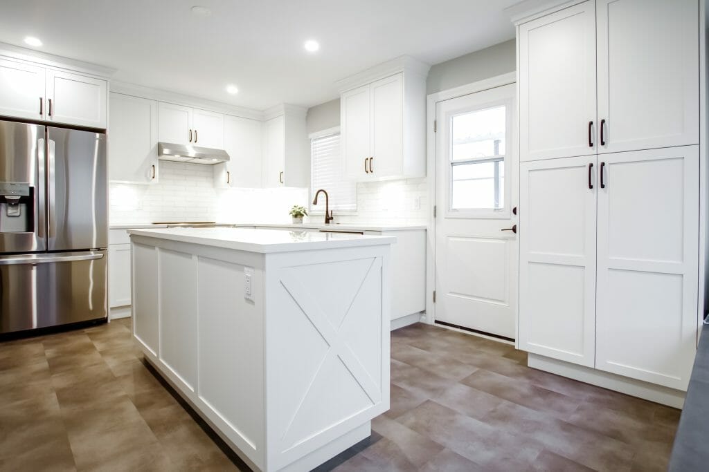 A newly finished kitchen in white with country-style cabinets and a large kitchen island.