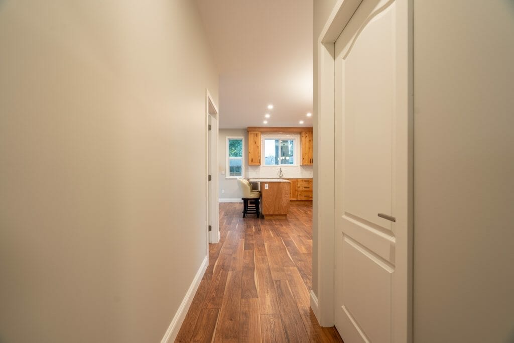 A view from the hallway of a refinished kitchen with natural wooden cabinets.