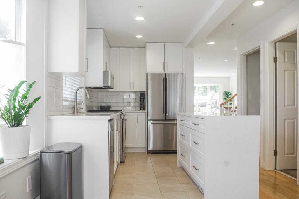 A modern white kitchen with stainless steel appliances and a large island.